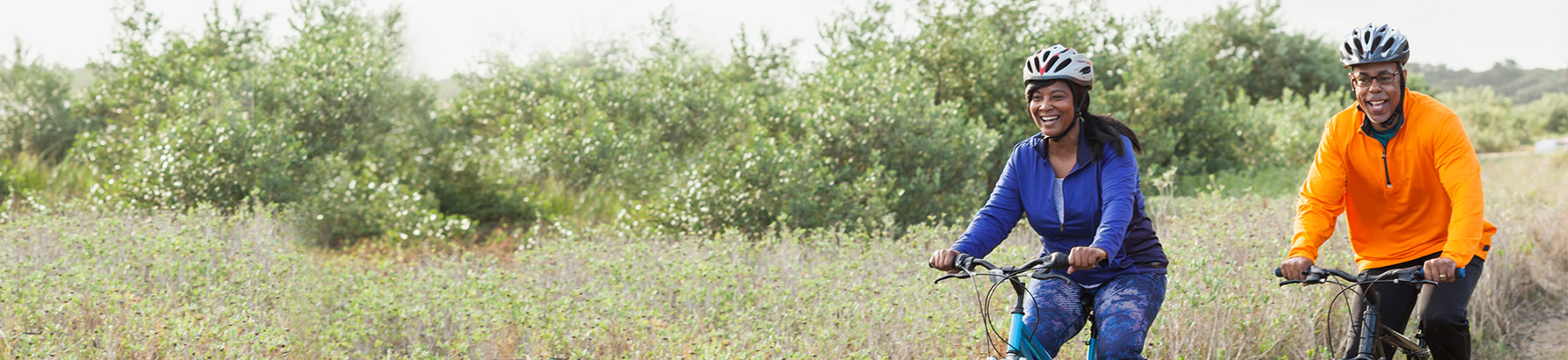 Couple riding bicycles in field